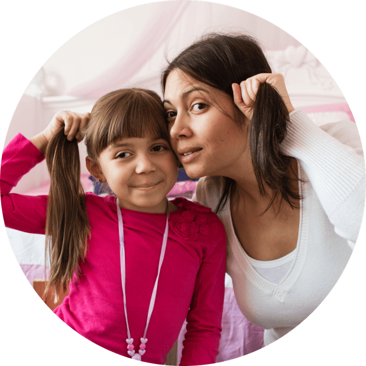 Mother and daughter holding their hair in a side ponytail.