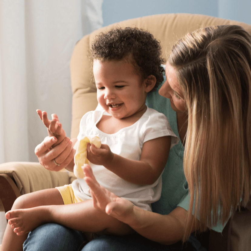 Mother sitting in a chair playing with her child on her lap.